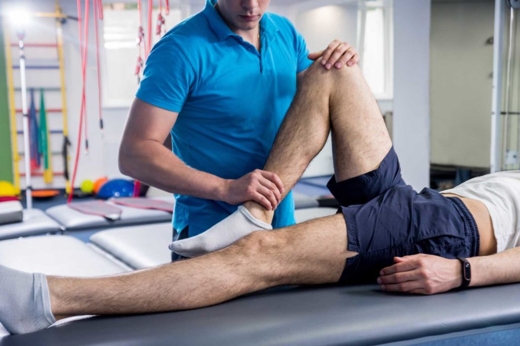 chiropractor stretching runners leg on treatment table